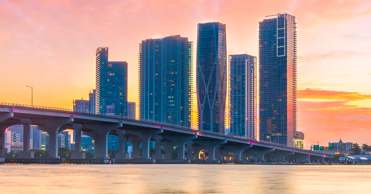 Atardecer en Miami con vista al puente y rascacielos modernos reflejando la luz del sol.